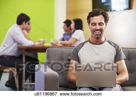 Stock Photo - Man Sitting On Sofa And Working In Design Studio . Fotosearch