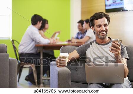 Stock Photography - Man Sitting On Sofa And Working In Design Studio . Fotosearch