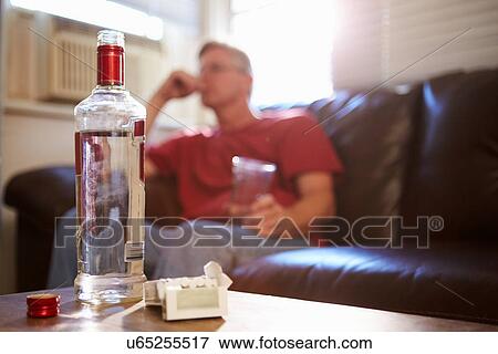 Man Sitting On Sofa With Bottle Of Vodka And Cigarettes View Large Photo Image Stock Photo - Man Sitting On Sofa With Bottle Of Vodka And Cigarettes. Fotosearch