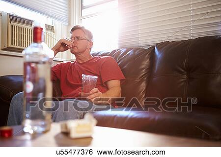 Man Sitting On Sofa With Bottle Of Vodka And Cigarettes View Large Photo Image Stock Photograph - Man Sitting On Sofa With Bottle Of Vodka And Cigarettes. Fotosearch