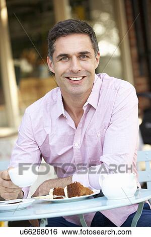 Stock Photograph - Man sitting outside café. Fotosearch