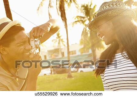 Stock Photograph - Man Taking Photograph Of Woman In Park. Fotosearch