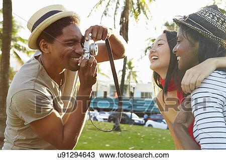 Man Taking Photograph Of Women In Park View Large Photo Image Stock Image - Man Taking Photograph Of Women In Park. Fotosearch