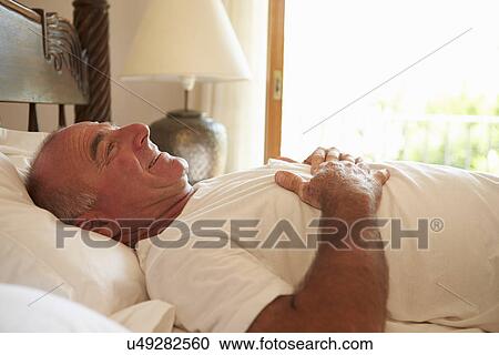 Stock Image - Man Waking Up In Bed In Morning. Fotosearch