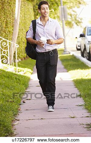 Stock Photo - Man Walking Along Street To Work Listening To Music. Fotosearch