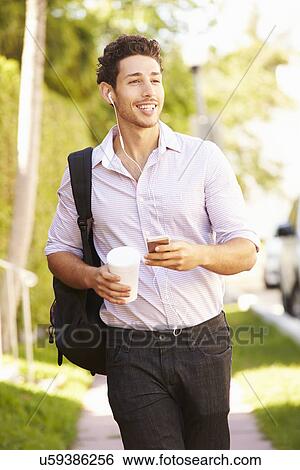 Stock Photograph - Man Walking Along Street To Work Listening To Music. Fotosearch
