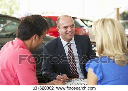 Stock Image - Man working in car showroom. Fotosearch