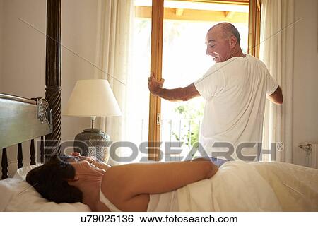 Stock Photograph - Mature Couple Waking Up In Bed In Morning. Fotosearch