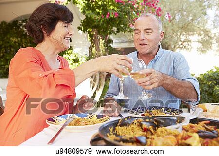 Stock Photo - Mature Hispanic Couple Enjoying Outdoor Meal At Home . Fotosearch