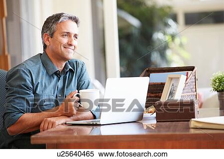 Mature Hispanic Man Using Laptop On Desk At Home View Large Photo Image Stock Photography - Mature Hispanic Man Using Laptop On Desk At Home. Fotosearch