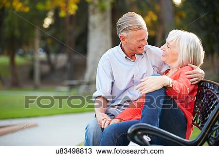 Stock Image - Mature Romantic Couple Sitting On Park Bench Together. Fotosearch