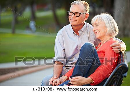 Stock Photo - Mature Romantic Couple Sitting On Park Bench Together. Fotosearch
