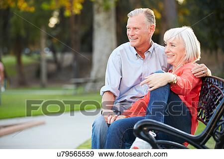 Stock Photo - Mature Romantic Couple Sitting On Park Bench Together. Fotosearch