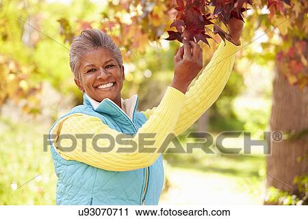 Stock Image - Mature Woman Relaxing In Autumn Landscape. Fotosearch