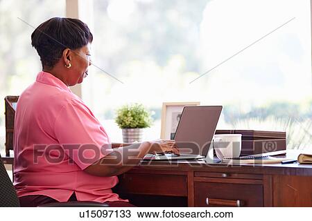 Mature Woman Using Laptop On Desk At Home View Large Photo Image Stock Image - Mature Woman Using Laptop On Desk At Home. Fotosearch