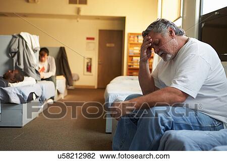 Stock Image - Men Lying On Beds In Homeless Shelter. Fotosearch