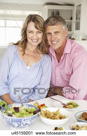 Stock Image - Mid age couple enjoying meal at home. Fotosearch
