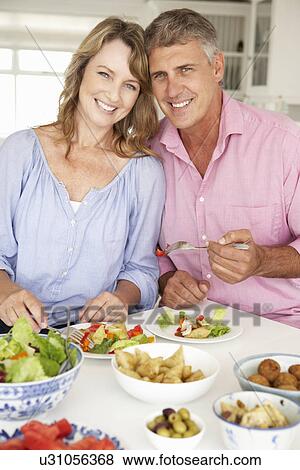 Mid age couple enjoying meal at home View Large Photo Image Stock Photo - Mid age couple enjoying meal at home. Fotosearch