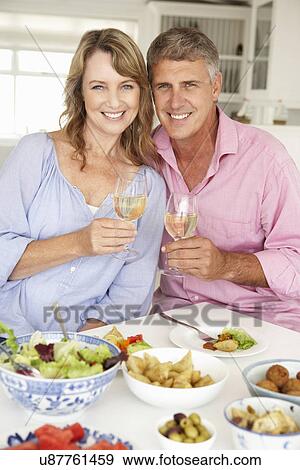 Stock Photo - Mid age couple enjoying meal at home. Fotosearch