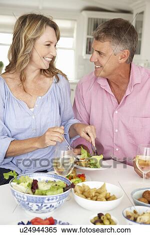 Mid age couple enjoying meal at home View Large Photo Image Stock Photography - Mid age couple enjoying meal at home. Fotosearch