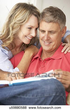 Stock Photo - Mid age couple reading book together. Fotosearch