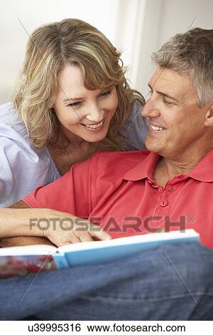 Stock Photograph - Mid age couple reading book together. Fotosearch