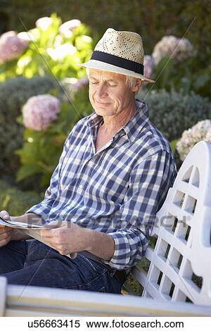 Mid age man reading newspaper in garden View Large Photo Image Stock Photography - Mid age man reading newspaper in garden. Fotosearch