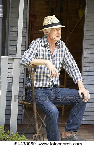 Stock Photo - Mid age man resting on veranda. Fotosearch