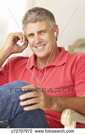 Stock Image - Mid age man wearing earphones. Fotosearch