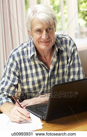 Stock Image - Mid age man working in home office. Fotosearch