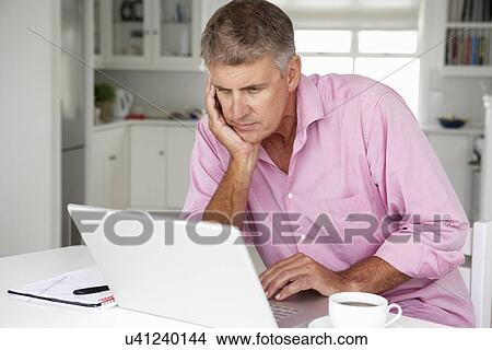 Mid age man working on laptop at home View Large Photo Image Picture - Mid age man working on laptop at home. Fotosearch