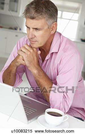 Stock Photography - Mid age man working on laptop at home. Fotosearch