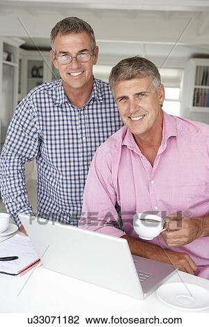 Mid age men working on laptop at home View Large Photo Image Stock Image - Mid age men working on laptop at home. Fotosearch