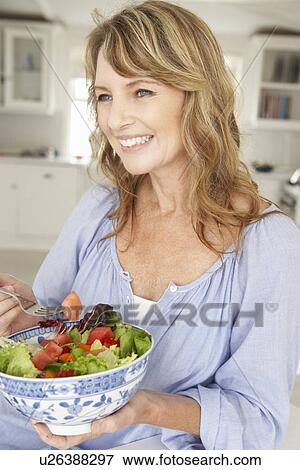 Mid age woman eating salad View Large Photo Image Stock Photo - Mid age woman eating salad. Fotosearch