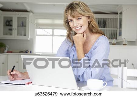 Mid age woman working at home on laptop View Large Photo Image Stock Photo - Mid age woman working at home on laptop. Fotosearch