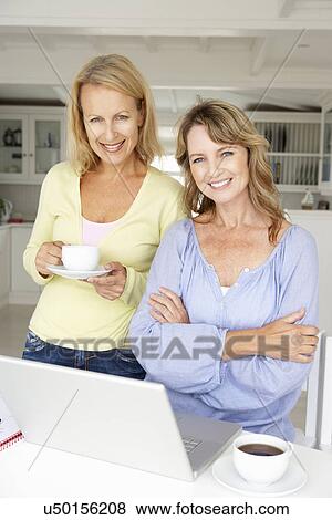 Stock Photo - Mid age women using laptop at home. Fotosearch