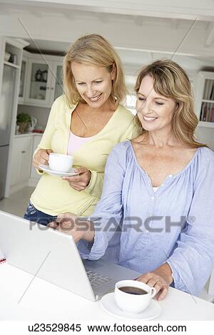 Stock Photography - Mid age women using laptop at home. Fotosearch