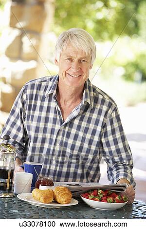 Middle aged man eating breakfast outdoors View Large Photo Image Stock Image - Middle aged man eating breakfast outdoors. Fotosearch