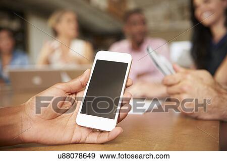 Stock Photo - Mobile Phone Being Used By Architect In Meeting. Fotosearch