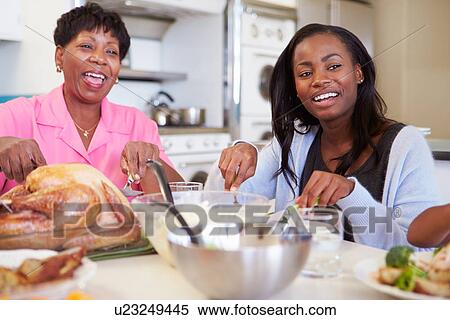 Stock Photography - Mother And Adult Daughter Having Family Meal At Table. Fotosearch