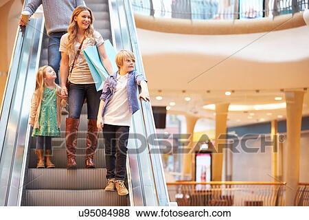 Stock Photo - Mother And Children On Escalator In Shopping Mall. Fotosearch