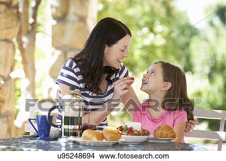 Mother and daughter eating breakfast outdoors View Large Photo Image Picture - Mother and daughter eating breakfast outdoors. Fotosearch