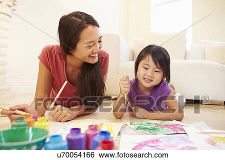 Stock Photograph - Mother And Daughter Lying On Floor And Painting Picture . Fotosearch