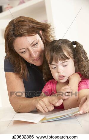 Stock Photograph - Mother and Downs Syndrome girl reading. Fotosearch