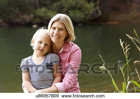 Mother and young daughter sitting by lake View Large Photo Image Stock Photo - Mother and young daughter sitting by lake. Fotosearch