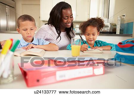 Stock Photo - Mother Helping Children With Homework At Table. Fotosearch