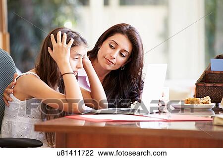 Stock Image - Mother Helping Stressed Teenage Daughter Looking At Laptop. Fotosearch