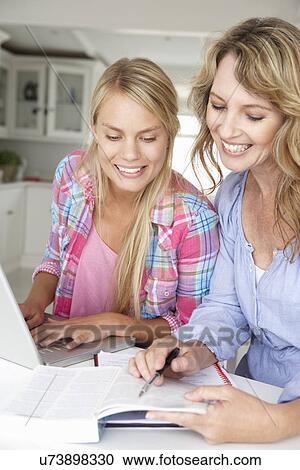 Stock Image - Mother helping teenage daughter with homework. Fotosearch