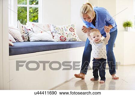 Stock Image - Mother Helping Young Son As He Learns To Walk. Fotosearch