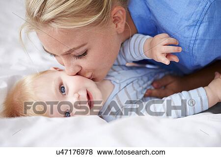 Mother Kissing Baby Son As They Lie In Bed Together View Large Photo Image Stock Photo - Mother Kissing Baby Son As They Lie In Bed Together. Fotosearch